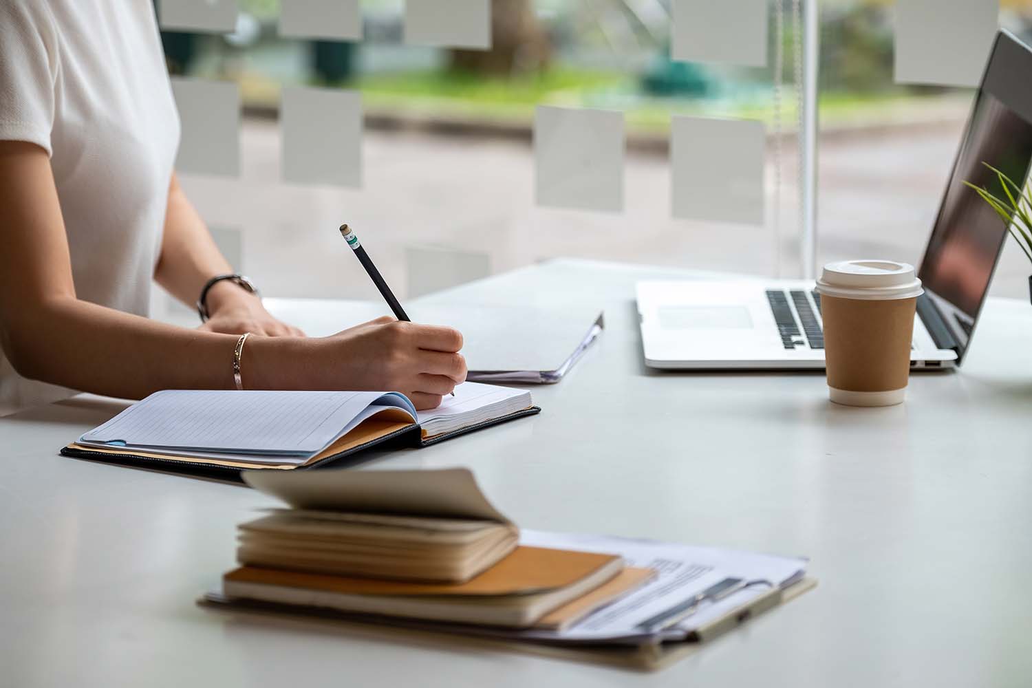 Eine Frau aus nächster Nähe macht sich Notizen auf ihrem Notizbuch für Online-Kurse, Lernideen und Notizen. Online-Bildung mit Laptop-Computer