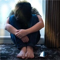 Porträt eines Teenagers, der allein mit seinem Smartphone im Zimmer sitzt und sich durch Cyber-Mobber in den sozialen Medien verletzt, ängstlich und deprimiert fühlt. Technologie verursacht psychische Probleme bei Teenagern.